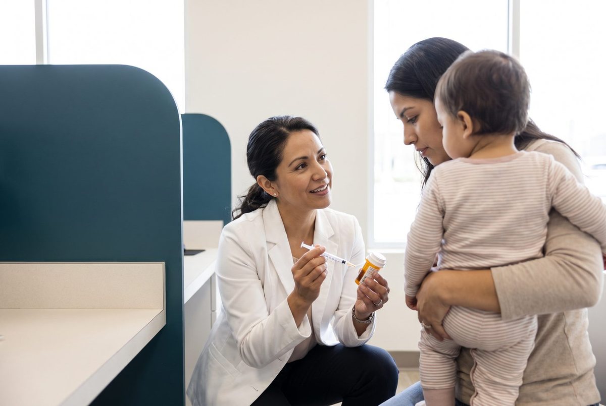 A pharmacist talking with a parent holding a small child.